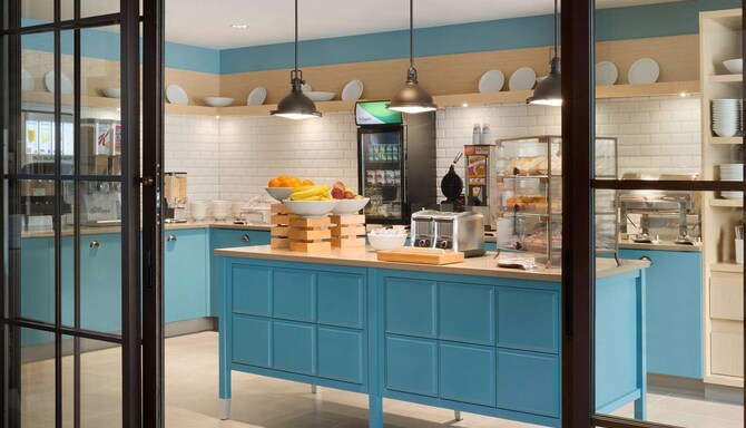 Frukostrum med en kaffebröd, fruktskålar och kylskåp med yogurt