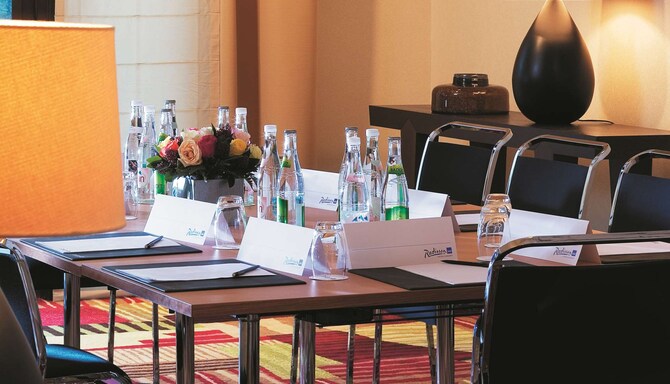 Radisson Blu Hotel Paris, Marne-la-Vallée - Salle de réunion, table avec cartes Radisson, blocs-notes et eau