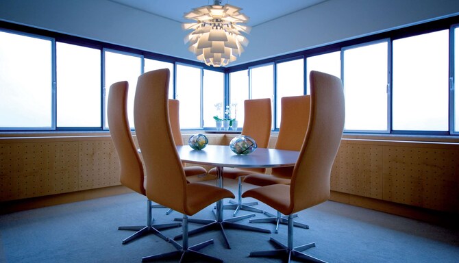 A table with chairs in a conference room with windows