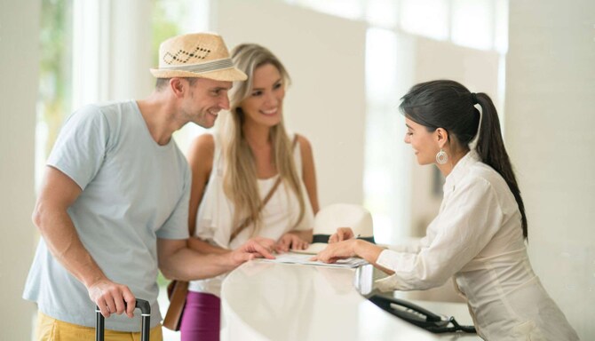 Man and woman checking in at front desk with attendant.