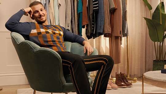 A well dressed smiling man sitting in a chair.