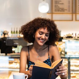 Blog images - Person drinking coffee and reading a book - 5 dining spots in Riga