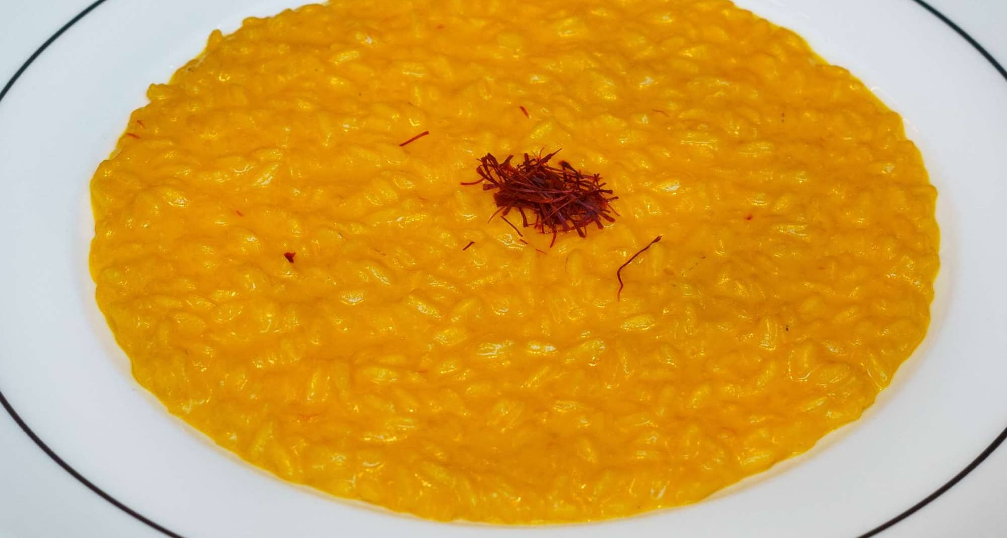 Blog images - 2023 - Culinary Tales Flavors of Milan with Luca Milanese Saffron Risotto Recipe risotto on a black table