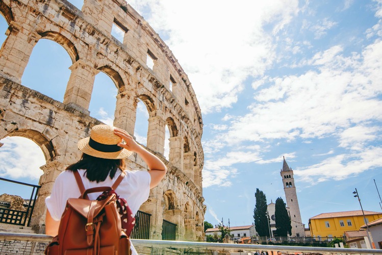Blog images - Where to Go in August: Travel Ideas - woman looking at coloseum in Pula