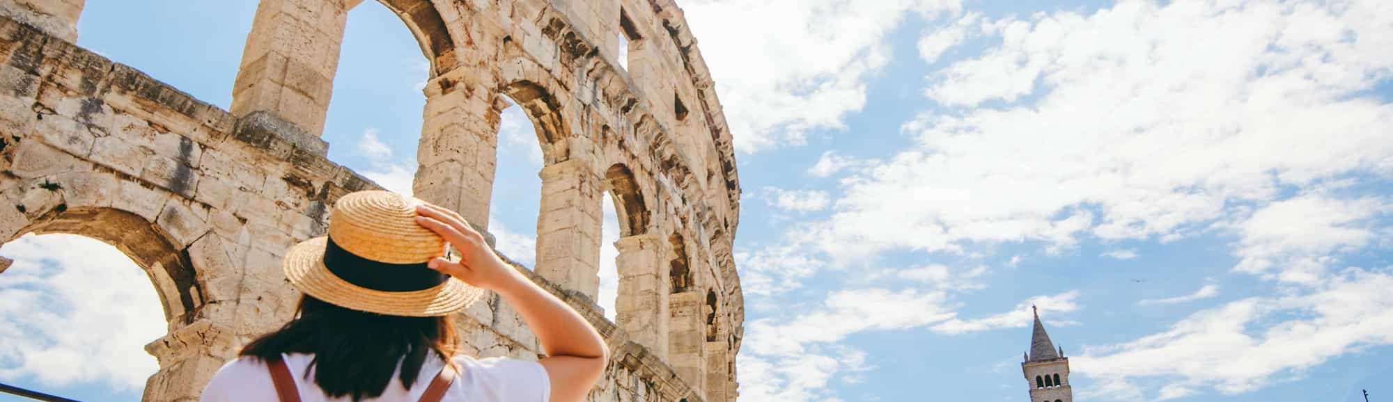 Blog images - Where to Go in August: Travel Ideas - woman looking at coloseum in Pula