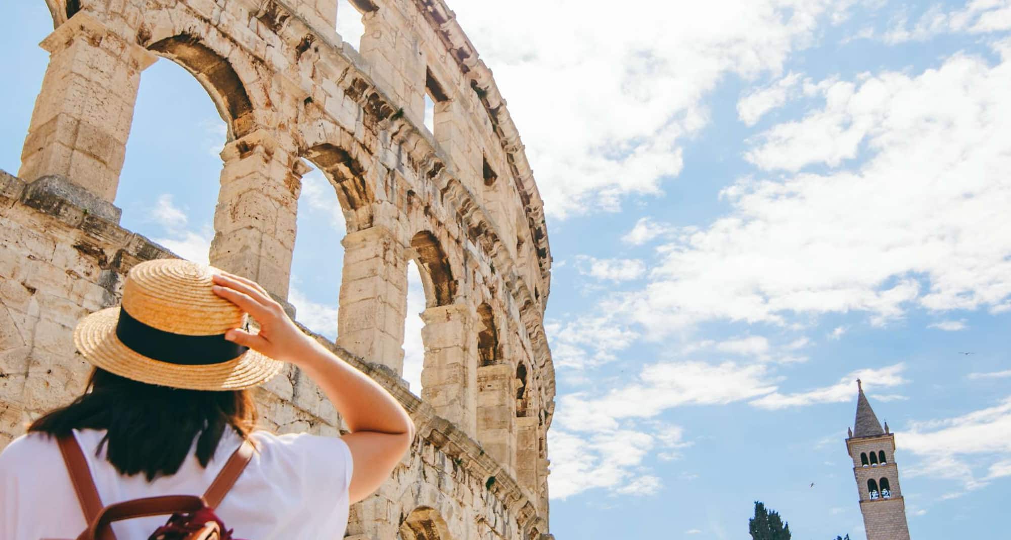 Blog images - Where to Go in August: Travel Ideas - woman looking at coloseum in Pula