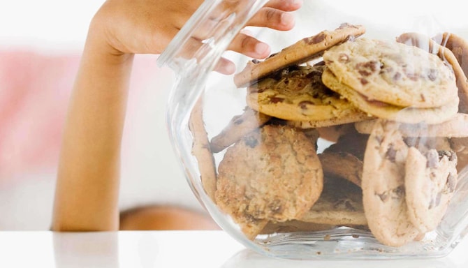 Child s hand reaching into jar of fresh-baked cookies