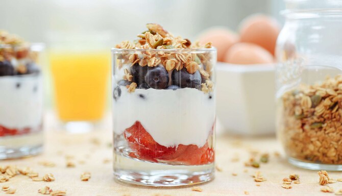 A parfait glass layered with yogurt, strawberries, blueberries and granola