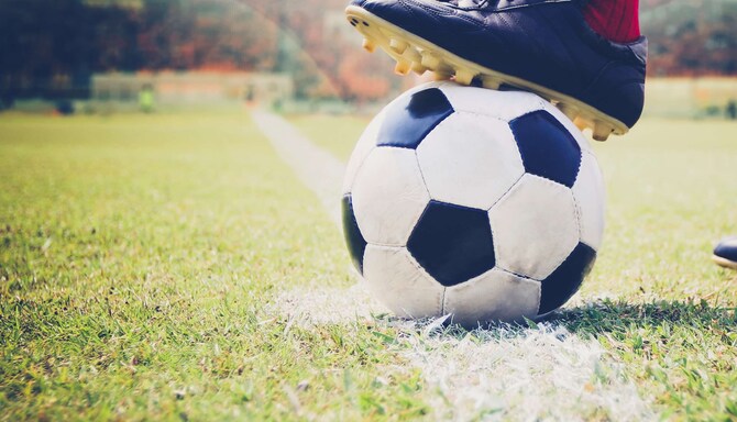 En närbild på en fotbollsspelares fot som vilar på en fotboll