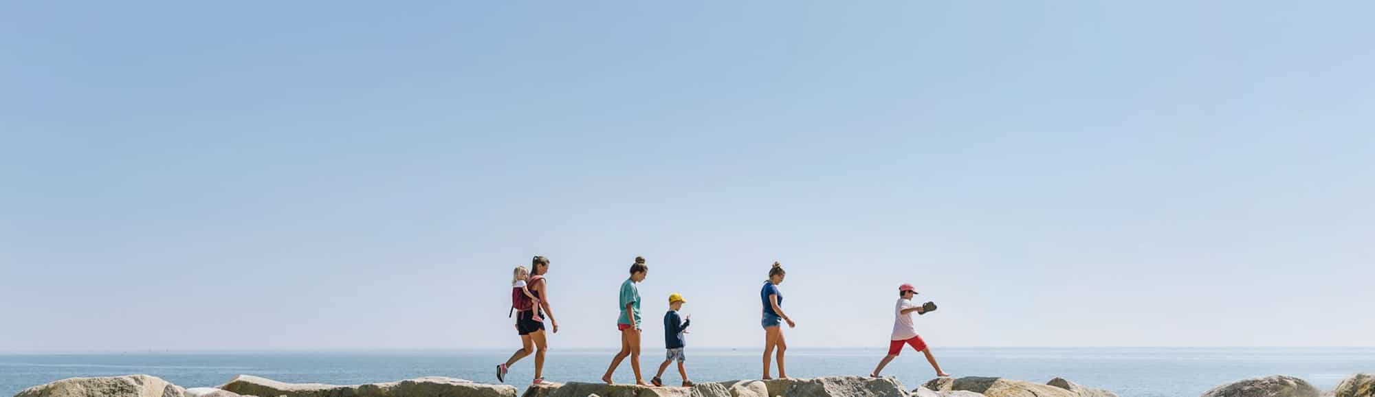 Famille se promenant le long d’une digue avec ciel bleu clair en fond.