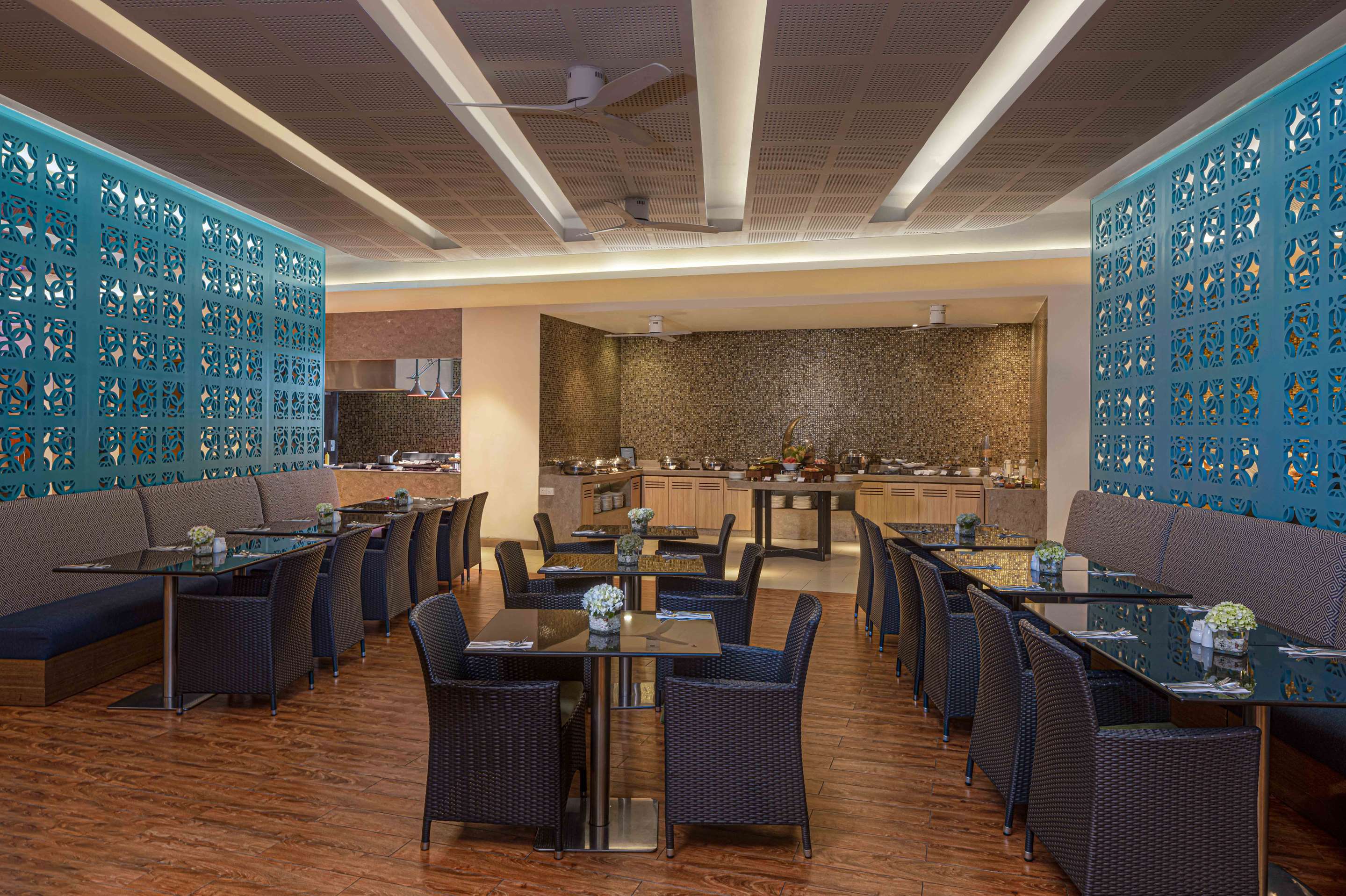 The restaurant: tables and wicker chairs between blue latticed screens, with the buffet counter at the far end