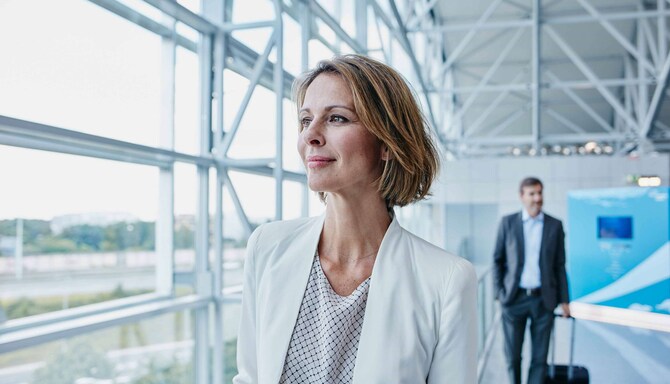 A business woman walking through an airport. - AMER Meetings - Get Rewarded Promotion