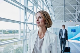 A business woman walking through an airport. - AMER Meetings - Get Rewarded Promotion