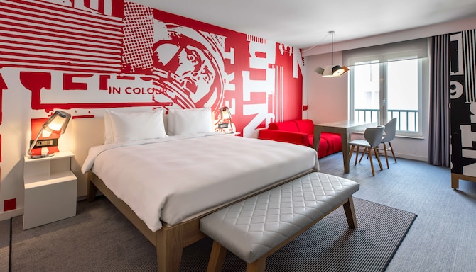 Radisson RED Brussels - Junior Suite room overview, king bed, sofa bed, seating area with table