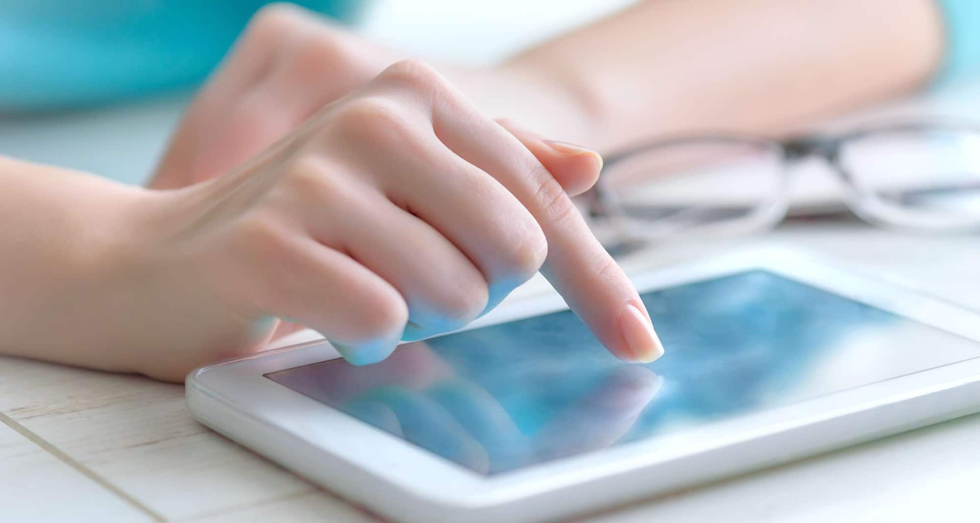 A woman's hand pointing to use an electronic tablet touchscreen