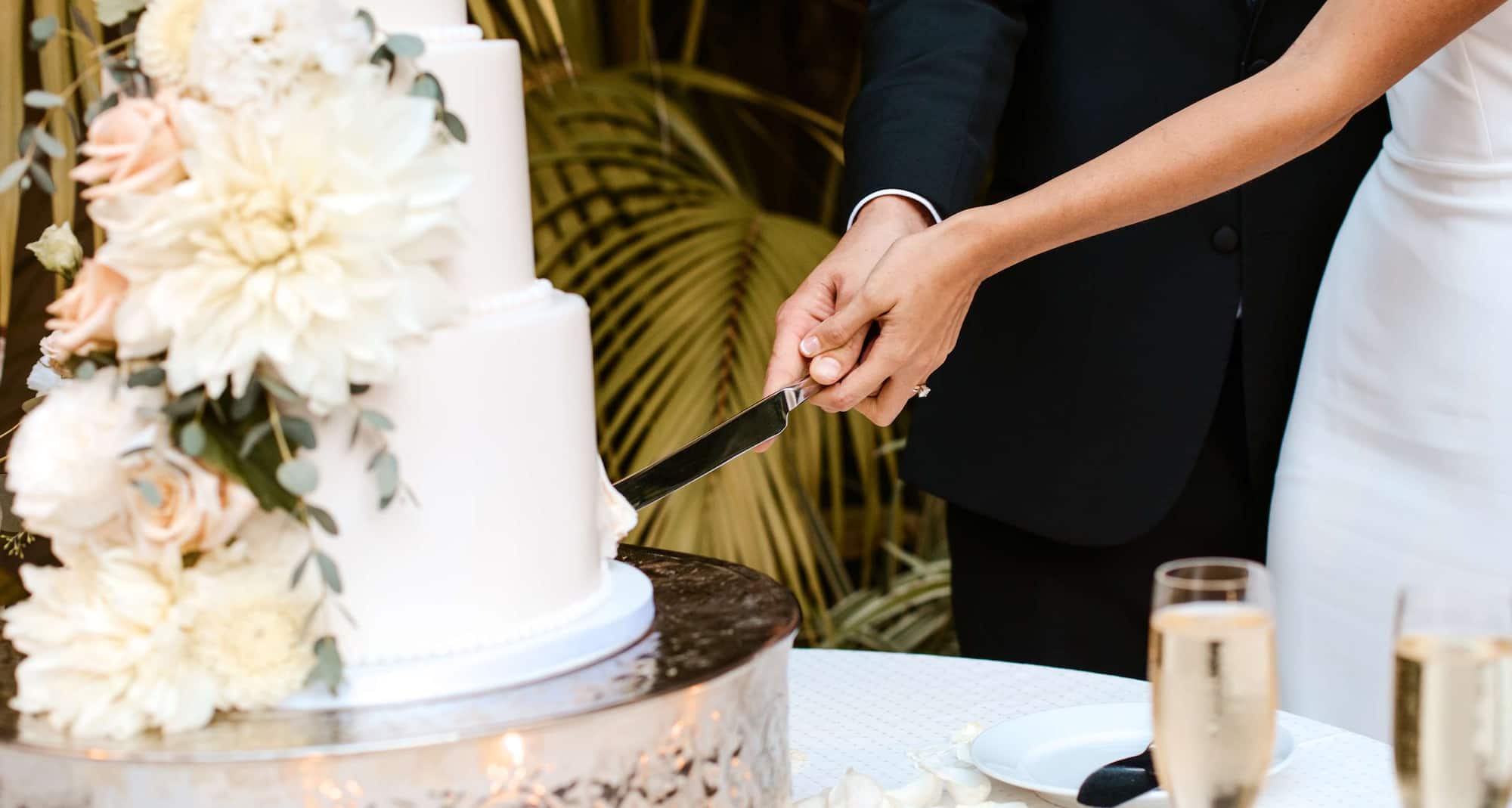 Weddings - Couple cutting wedding cake with white flowers