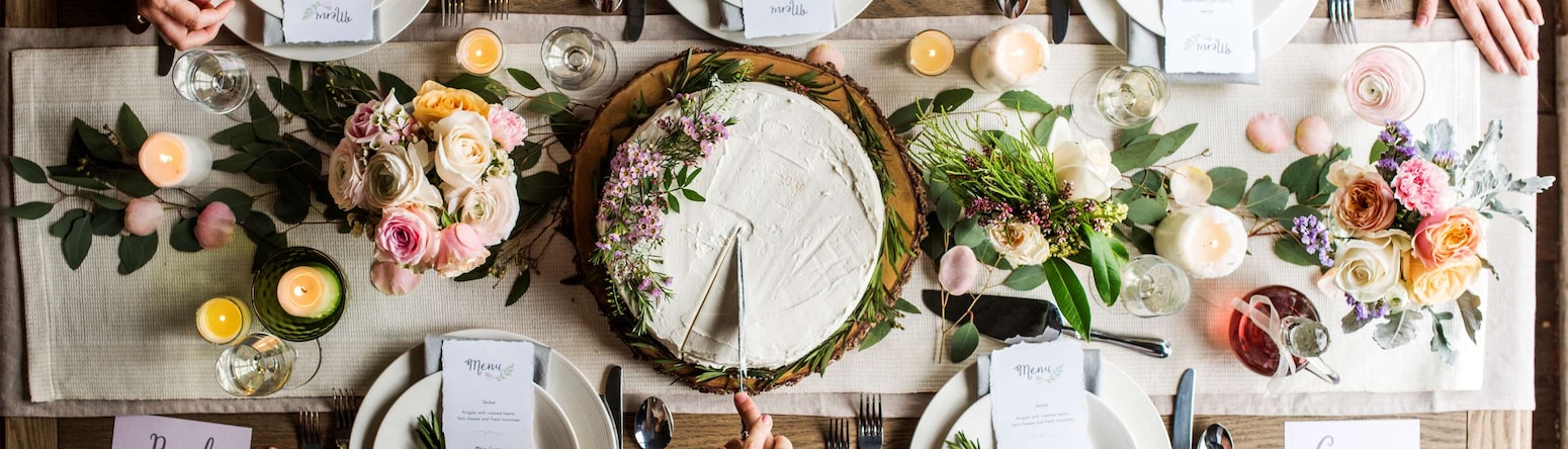 Hochzeiten - Braut und Bräutigam schneiden Kuchen auf dem Hochzeitsempfang an